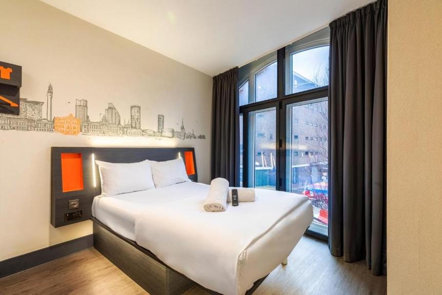 A room at easyHotel Birmingham with its Birmingham-skyline mural and arched window
